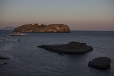 VENTOTENE, ITALY - JULY 14: Santo Stefano Island with its bourbon prison and Cala Nave beach at Sunset, on July 14 2020 in Ventotene, Italy. The prison camp was created under the Bourbons and restructured under Benito Mussolini on the nearby island of Santo Stefano. There, up to 700 opponents, including 400 communists, were incarcerated between 1939 and 1943. One of them was Altiero Spinelli who wrote there a text now known as the Ventotene Manifesto, promoting the idea of a federal Europe after the war. Prisoners also included former Italian President, the late Sandro Pertini. The tiny Island of Ventotene is one of the Pontine Islands in the Tyrrhenian Sea together with Santo Stefano, Ponza, Palmarola and Zannone, all located in the Tyrrhenian Sea. The island, the remains of an ancient volcano, is elongated, with a length of 3 kilometres (2 miles) and a maximum width of about 800 metres (2,625 feet).Since 1997 the marine area surrounding both Ventotene and Santo Stefano island is a protected area. Ventotene together with the Pontine Island of Ponza stayed free from COVID19 as no cases were registered since the Pandemic spread through out Italy in February 2020. (Photo by Alessandra Benedetti - Corbis/Corbis via Getty Images)